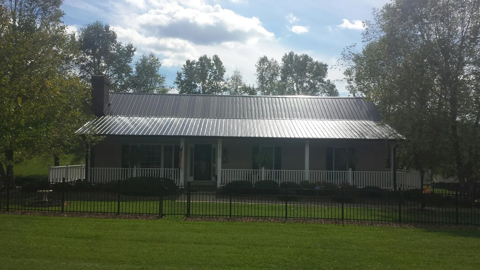 Gray metal roof on a brick ranch with a full width front porch — Gutter Guard Installation work by our crew in Pulaski