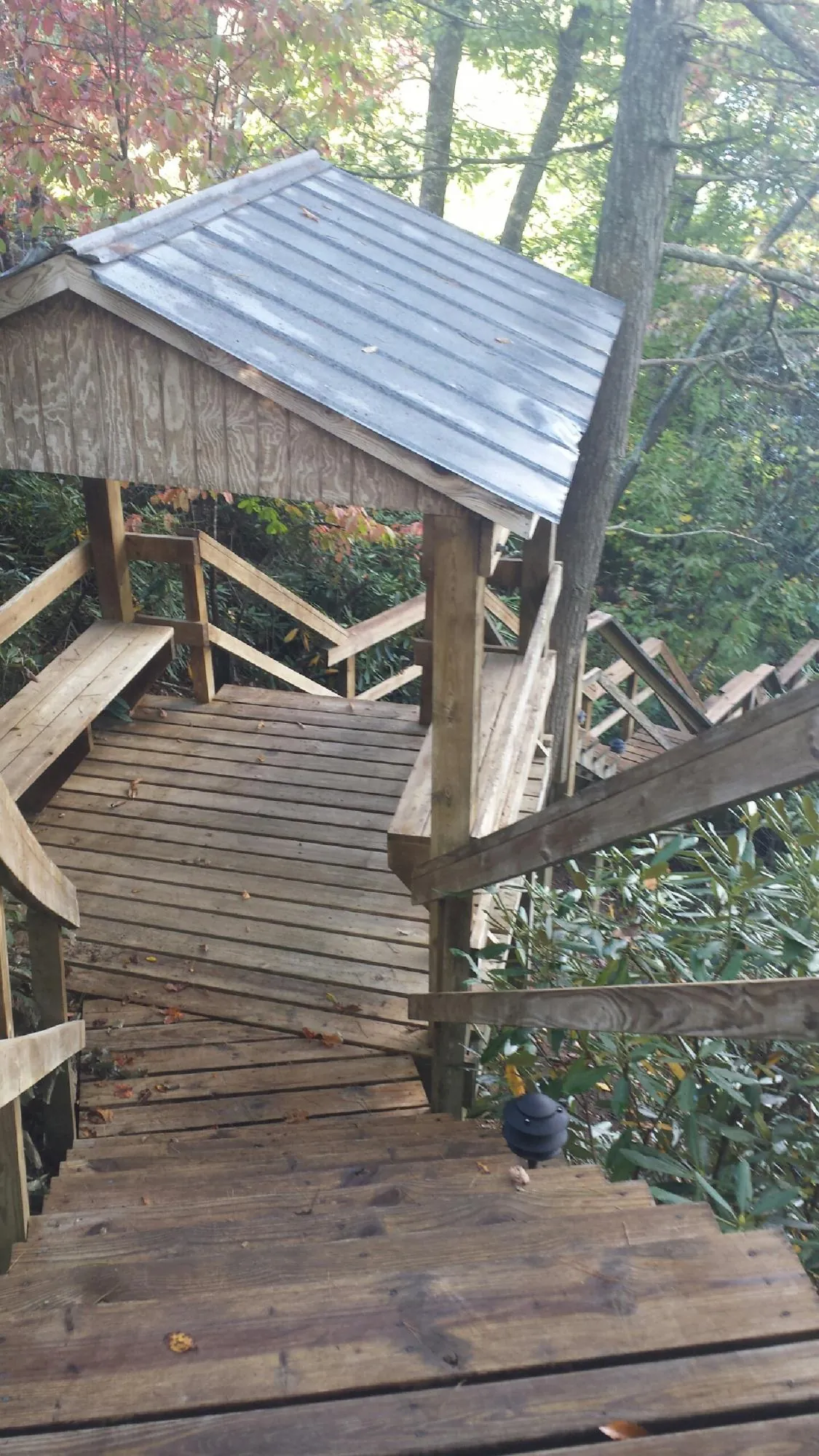 Metal roofed shelter over wooden steps on a wooded walkway — Skylight Repair & Installation work by our crew in Pulaski